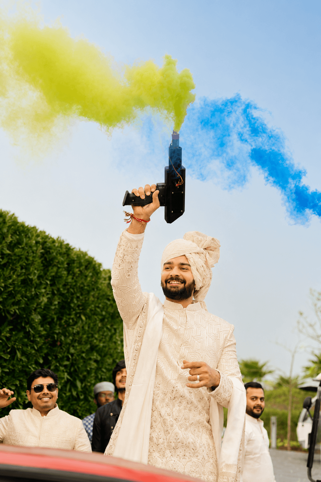 Groom celebrating amid colourful daytime smoke effects